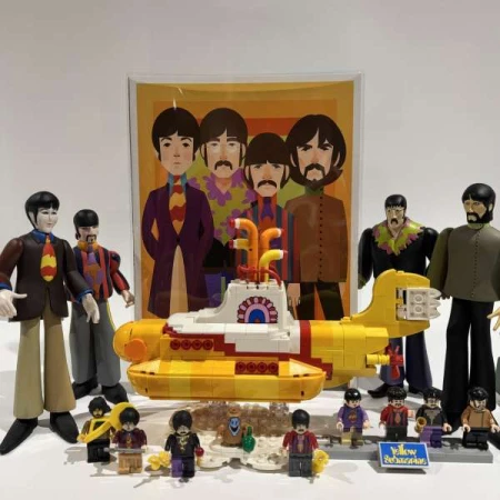 Yellow Submarine Lego set and figurines in front of a Beatles cartoon poster against a white background create a playful display.