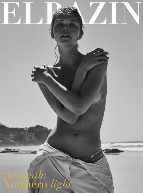 Black and white magazine cover featuring a topless adult female model posed on a beach, with ocean and dunes in the background.