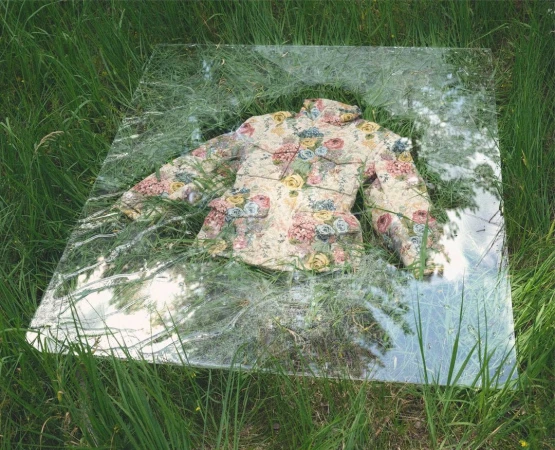Floral jacket is displayed on a mirror surrounded by green grass in an outdoor setting; spring day, natural lighting.