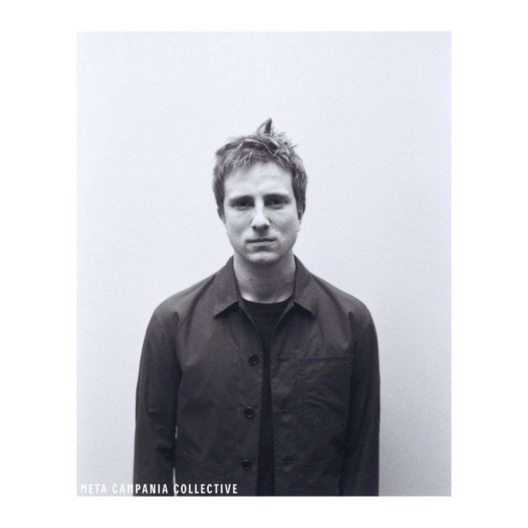Monochrome portrait of a young adult man in a jacket against a plain white background, focusing on his facial features and attire.
