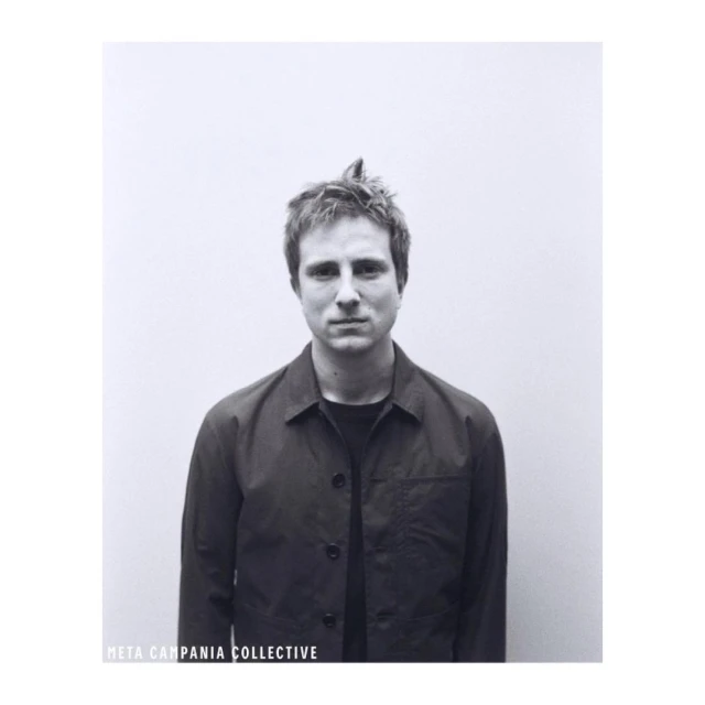 Monochrome portrait of a man wearing a dark button-up jacket against a plain background, photographed by Stefan Armbruster.