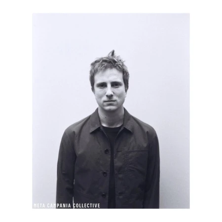 Monochrome portrait of a man wearing a dark button-up jacket against a plain background, photographed by Stefan Armbruster.