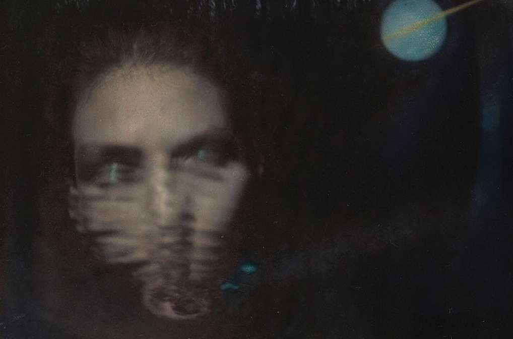 Portrait of a person with blurred features overlayed with water reflection textures and a celestial orb in a dark, atmospheric backdrop.