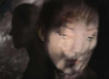 Close-up portrait with multiple exposure blur showing a person's face layered over a dark background by Stefan Milev.