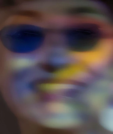 Abstract portrait of a person with sunglasses and colorful lighting effects, creating a dreamy and artistic blurred aesthetic.
