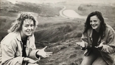 Black and white portrait of two young women outdoors gesturing with open hands, photographed by Stella Scott in London.
