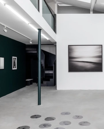 Monochrome interior view of a contemporary Milan gallery space with framed artwork on white and dark walls, captured by photographer Stephan Vanfleteren.