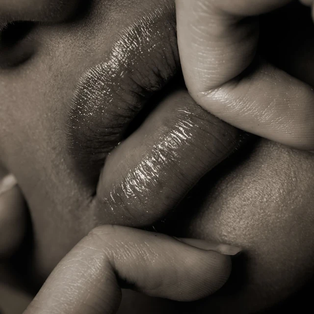Close-up of lips and fingers in a monochrome image showcasing beauty and skincare, highlighting the texture and detail of skin.