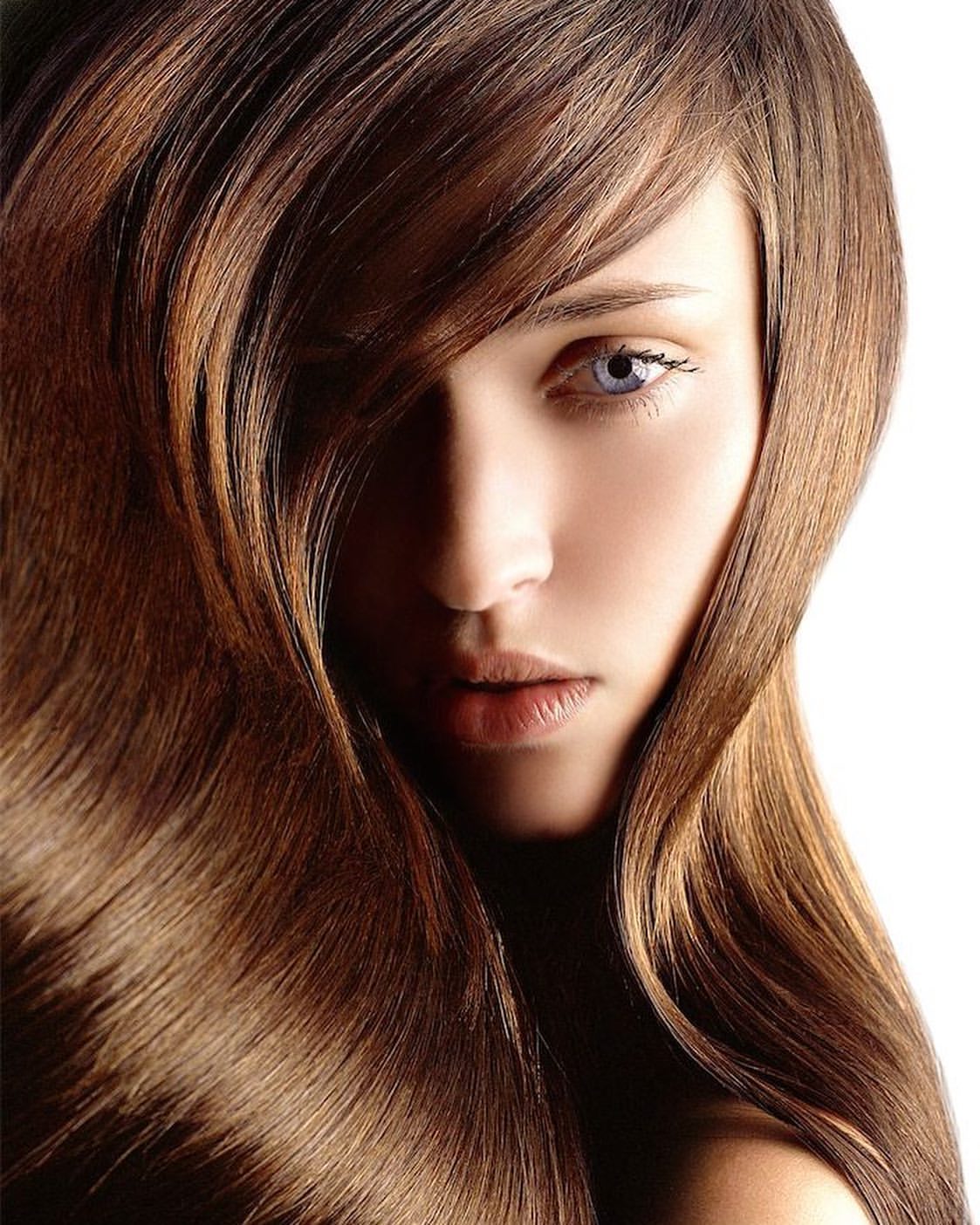 Close-up portrait of a woman with long brown hair partially covering her face against a bright white background