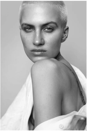 Close-up portrait of a woman with short blonde hair and a white collared shirt by photographer Stephane Coutelle
