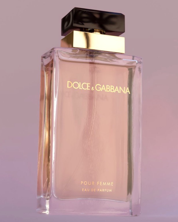 Dolce & Gabbana perfume bottle on a light pink background, featuring a clear glass bottle with gold accents and a black cap.