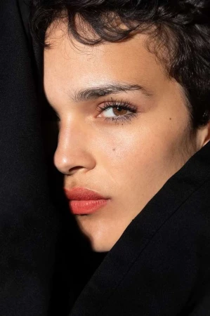 Close-up portrait of a woman with short dark hair and brown eyes wearing a black garment, photographed by Stephane Coutelle in Paris.