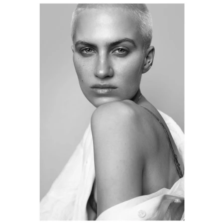 Close-up portrait of a woman with short blonde buzzcut wearing an open white shirt shot by Stephane Coutelle in Paris.