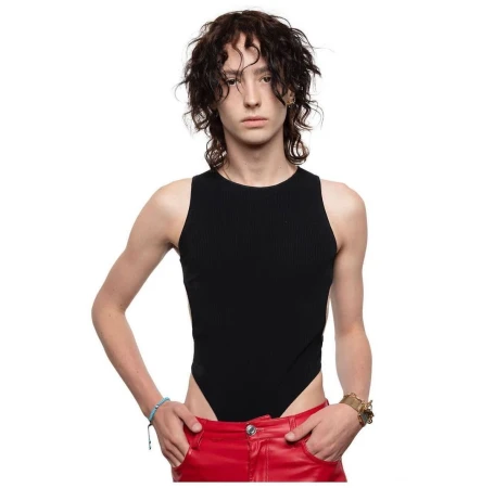 Model with dark wavy hair wearing a black sleeveless bodysuit and red trousers against a clean white background