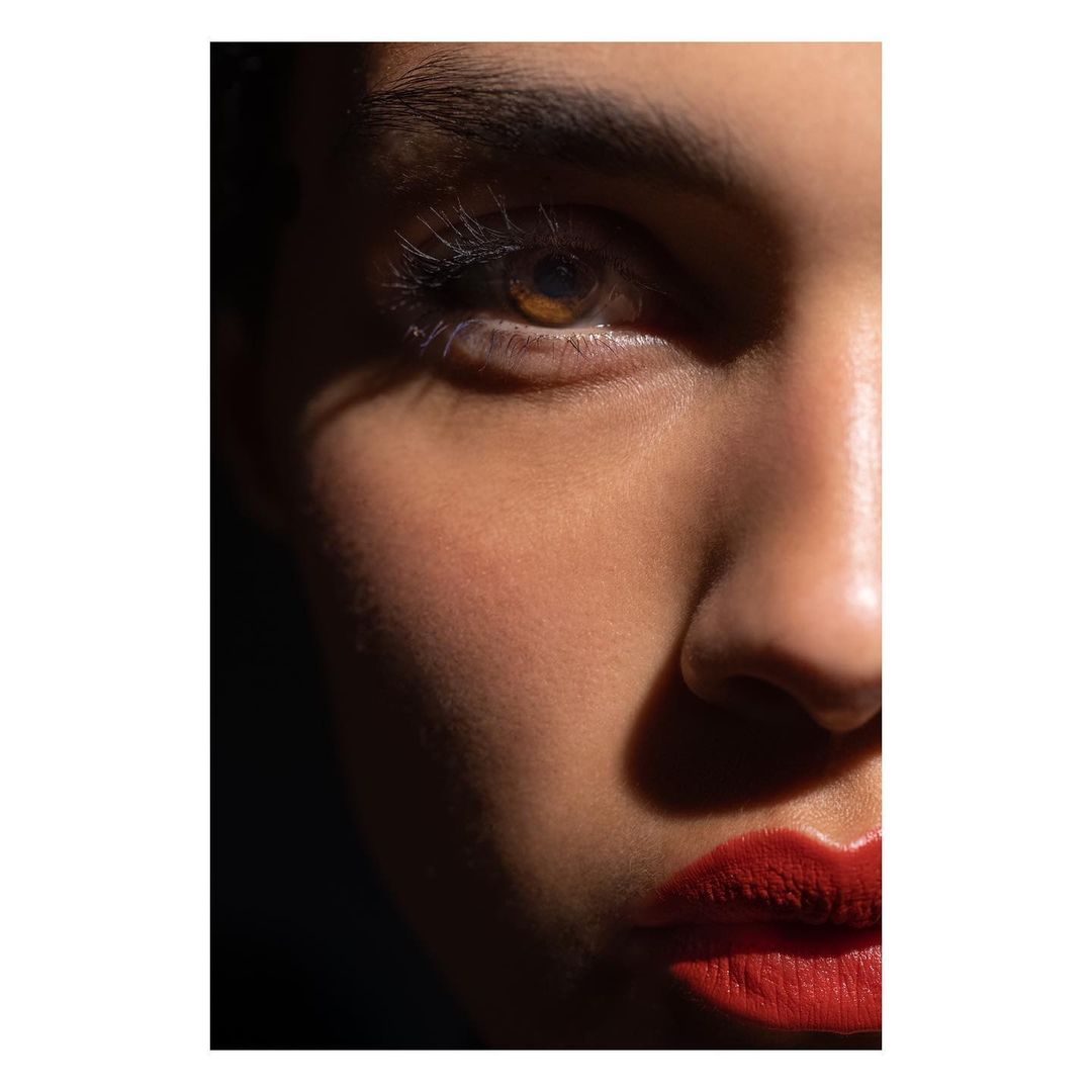 Close-up portrait of a woman's face with red lipstick and dramatic hard light by Stephane Coutelle