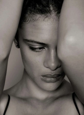 Close-up monochrome portrait of a woman with her arms raised framing her face by photographer Stephane Coutelle