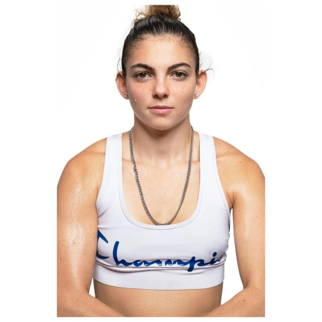 Confident athletic woman in white sports bra and silver chain against white background. Portrait shot of an adult female.