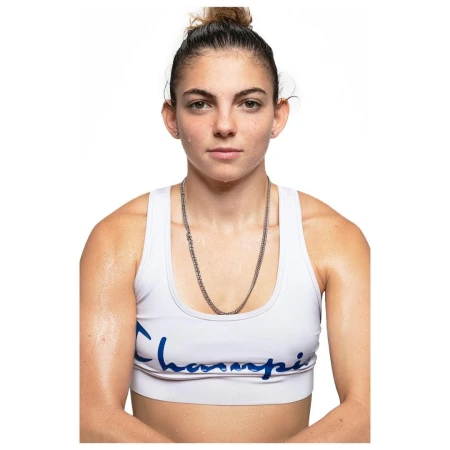 Confident athletic woman in white sports bra and silver chain against white background. Portrait shot of an adult female.