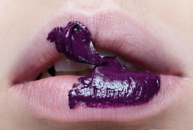Close-up macro shot of lips smeared with thick dark purple lipstick by photographer Stephane Coutelle