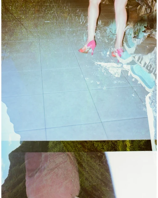 Legs and feet wearing pink heels are placed on tiled flooring with overlaid mountain and nature imagery creating a surreal collage.