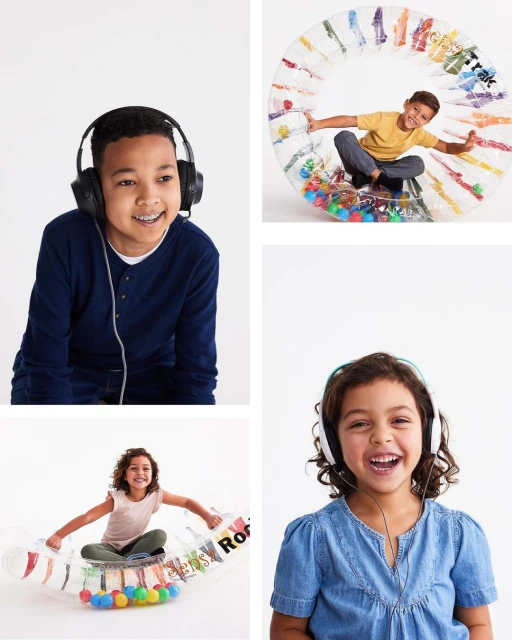 Four kids, two boys and two girls, are smiling while wearing headphones and playing in a studio with translucent play equipment.