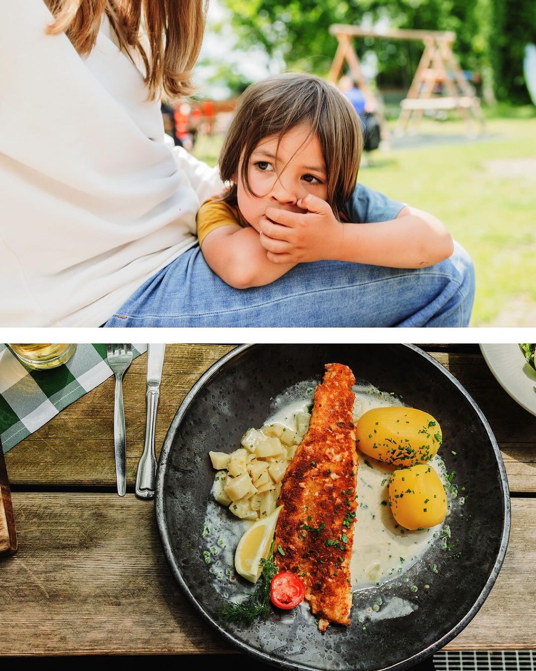 Child rests on a woman's lap outdoors, while a plate of fish with potatoes and lemon sits on a wooden table.