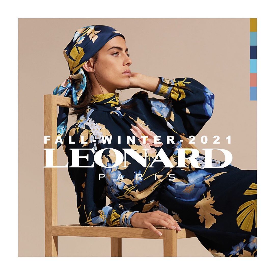 Elegant woman in floral headscarf and dress sitting on a chair in a fashion advertisement for LEONARD Paris Fall/Winter 2021 collection.