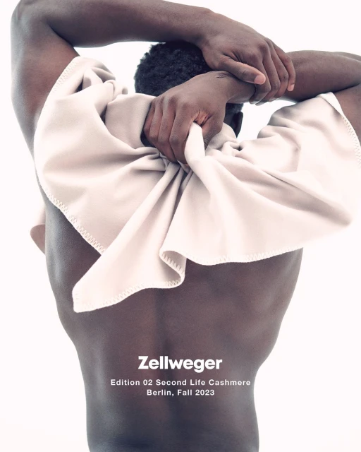 A Black male torso poses against a white background, draped with a soft beige textile, in a studio setting for a fashion editorial.