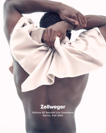 A Black male torso poses against a white background, draped with a soft beige textile, in a studio setting for a fashion editorial.