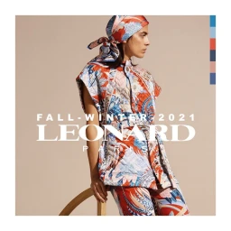 Woman wearing a floral patterned sleeveless top and matching headscarf leaning against a wooden stool against a beige background