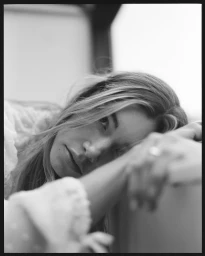Close up monochrome portrait of a woman resting her head on her arm with long hair and textured blouse by Stephanie Sian Smith