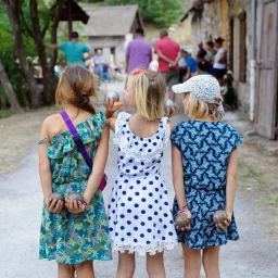 Three young girls holding pétanque balls behind their backs outdoors in Paris photographed by Stéphanie Tétu