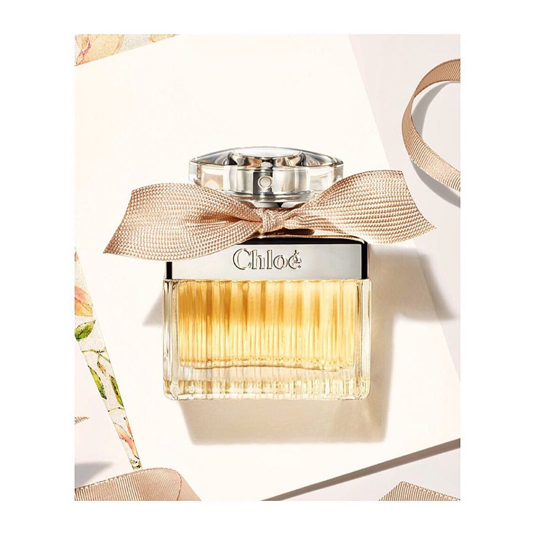 Chloe perfume bottle on a white background with floral accents and tan ribbon, elegant packaging for a fragrance product.