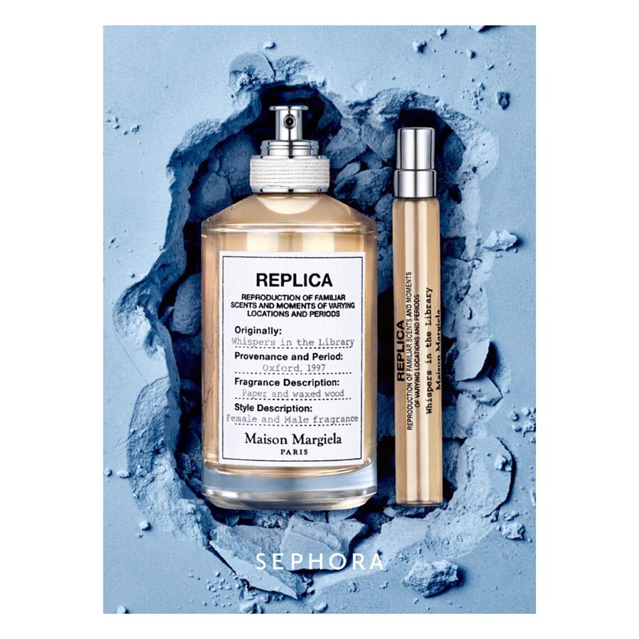 Two perfume bottles, one larger and one travel size, placed on a textured blue powder background in a studio shot, product photography.