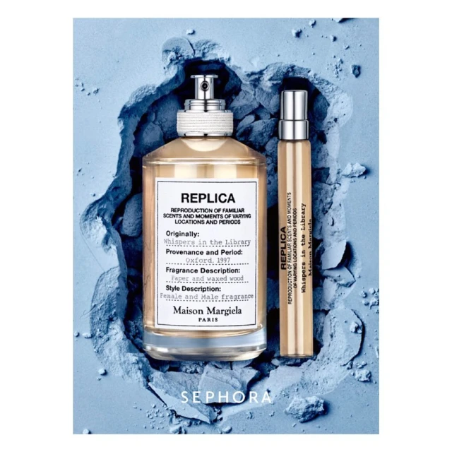 Two perfume bottles, one larger and one travel size, placed on a textured blue powder background in a studio shot, product photography.