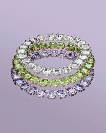 Three circular necklaces featuring clear, green, and purple square-cut gemstones, displayed on a reflective lavender surface in a studio setting.