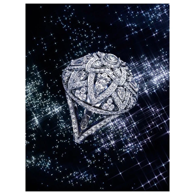 High-jewelry ring with diamond embellishments, set against a dark backdrop sprinkled with twinkling, star-like bokeh effects.