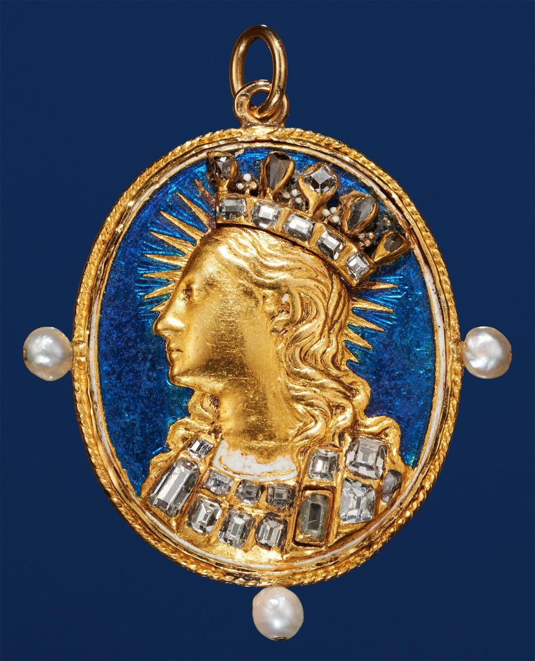 Close-up of a gold pendant featuring a woman's profile with a crown, pearls, and diamonds against a blue enamel backdrop.