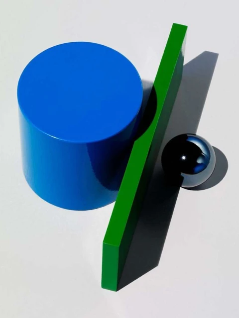 Abstract still life featuring a blue cylinder, green rectangle, and reflective black sphere on a white surface, casting shadows.