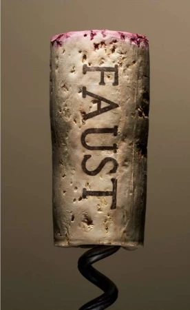 Macro photograph of a wine cork with the word 'FAUST' engraved, displaying its texture, with a wine opener corkscrew at the bottom.