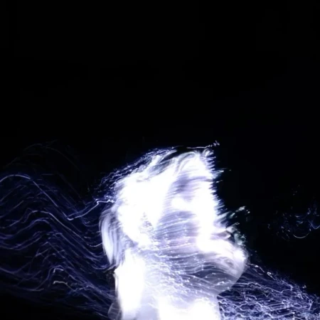 Abstract portrait of a person with long exposure and light painting, creating a glowing and ethereal aesthetic against a black backdrop.