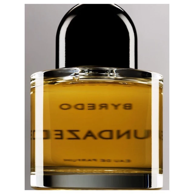 Byredo Sundazed fragrance in a square clear-glass bottle with a black dome-shaped cap against a neutral gray background in studio lighting.