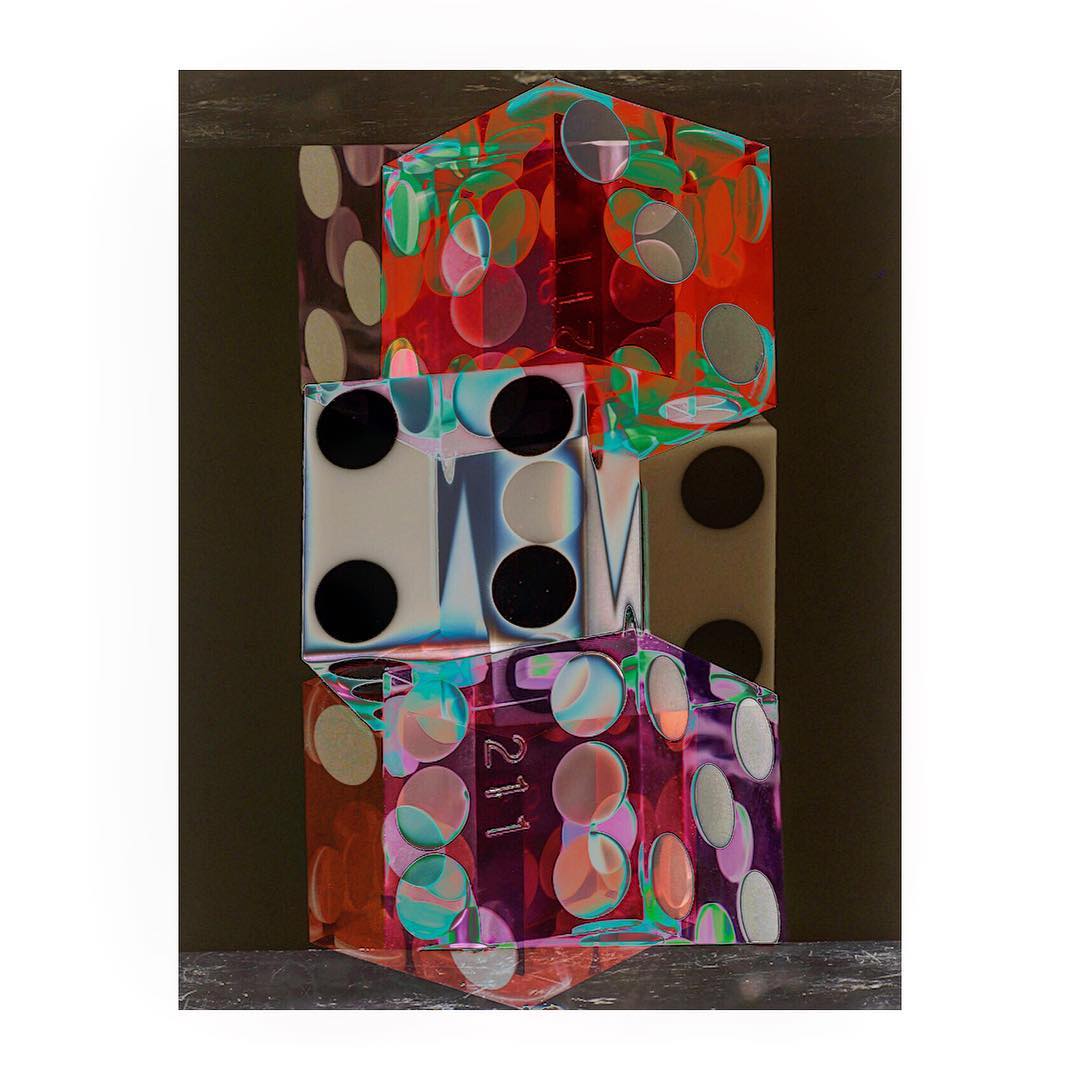 Abstract still life featuring a vertical stack of three translucent cubes with geometric designs and colorful patterns on a neutral backdrop.