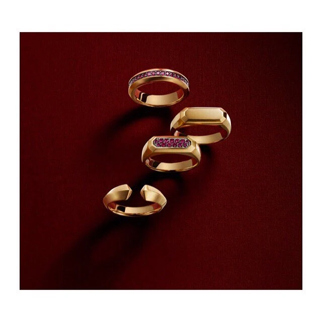 Four gold rings arranged diagonally against a dark red textured background, photographed by Stephen Lewis.