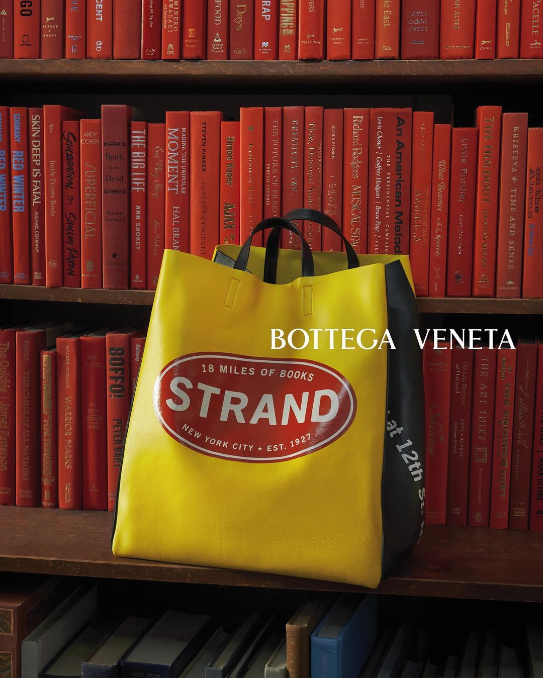 Yellow tote bag from Bottega Veneta and Strand Book Store on bookshelf with books, promoting fashion and book culture collaboration.