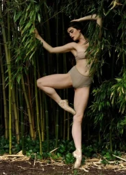 Ballet dancer en pointe posing amidst dense green bamboo stalks in a garden setting