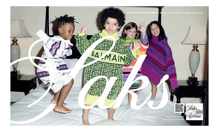 Four children in designer sweaters jump on a white bed in a studio ad. The kids are wearing Balmain, Christopher John Rogers and rag & bone sweaters.