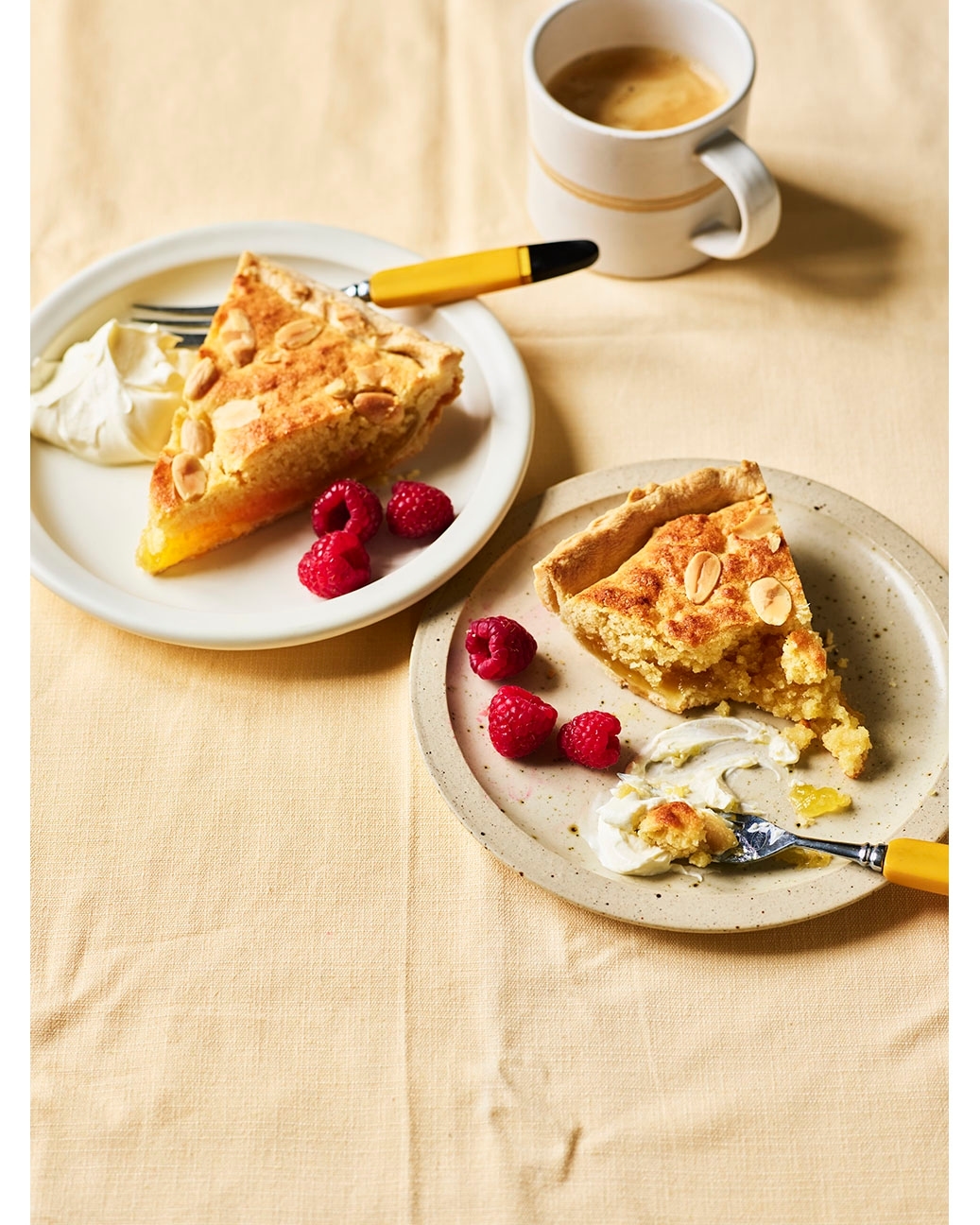 Two slices of pie on plates with raspberries and a coffee mug. Dessert food photography of a pie with pastry and fruit topping.