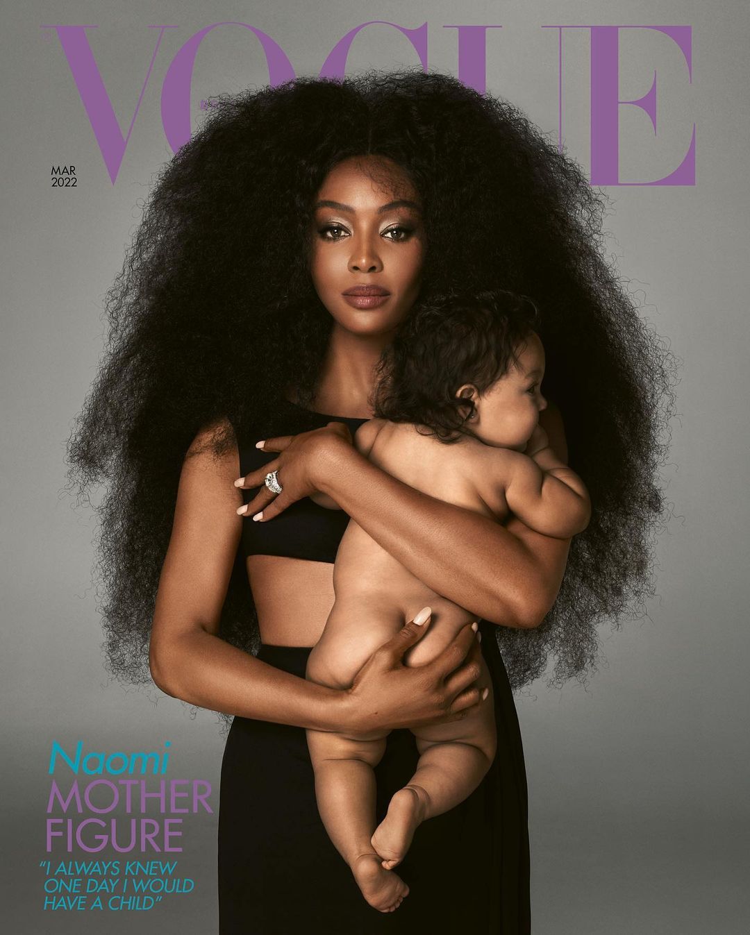 Vogue cover featuring Naomi Campbell holding her child, both facing forward. Campbell wears a black dress against a gray background.