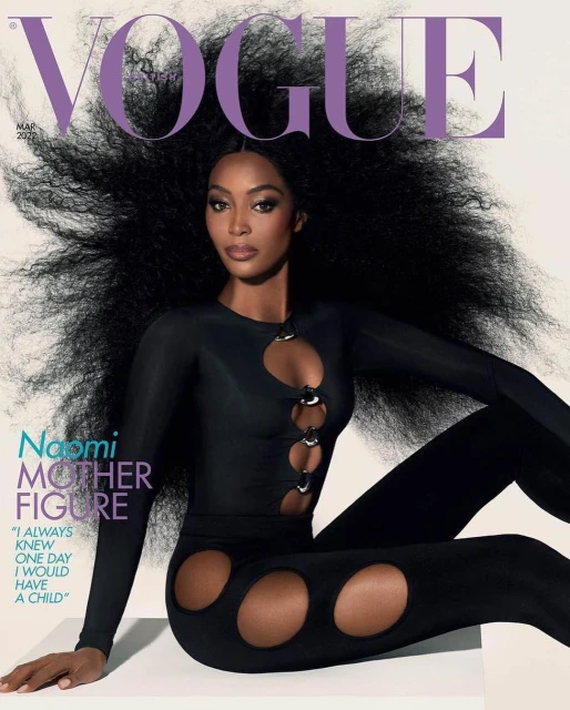 Naomi Campbell poses on a magazine cover in a black catsuit with circular cutouts, against a gradient white background. Big hair, close-up.